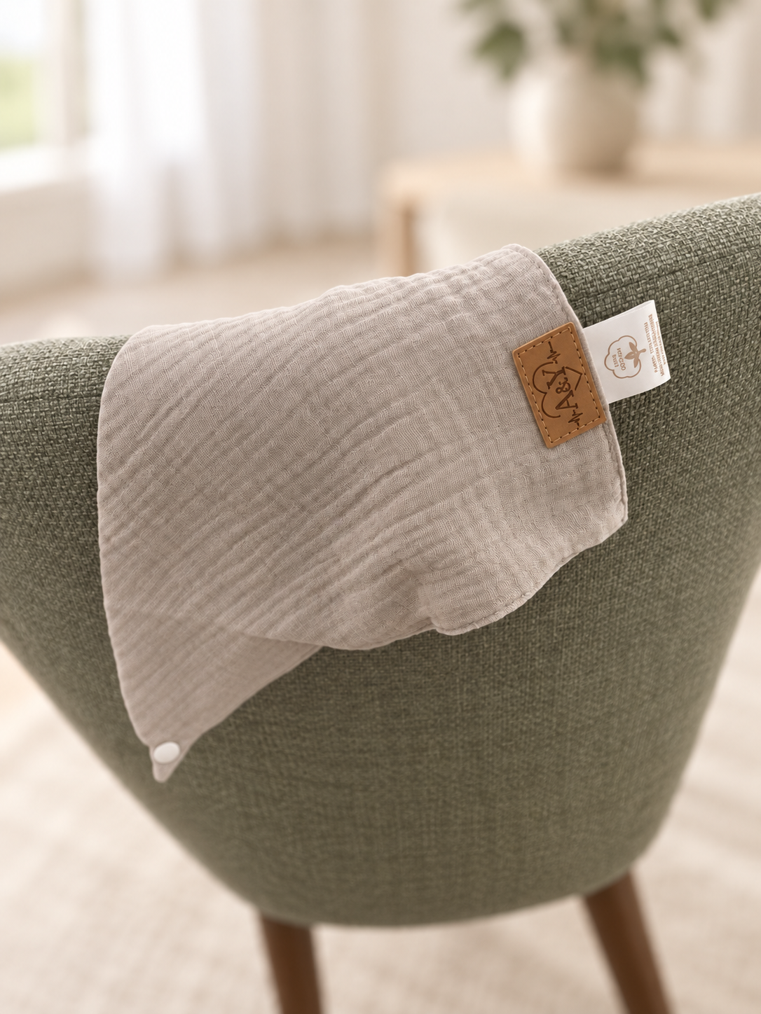 Bandana MINUS gris drapé sur une chaise sauge, montrant la souplesse du tissu.
