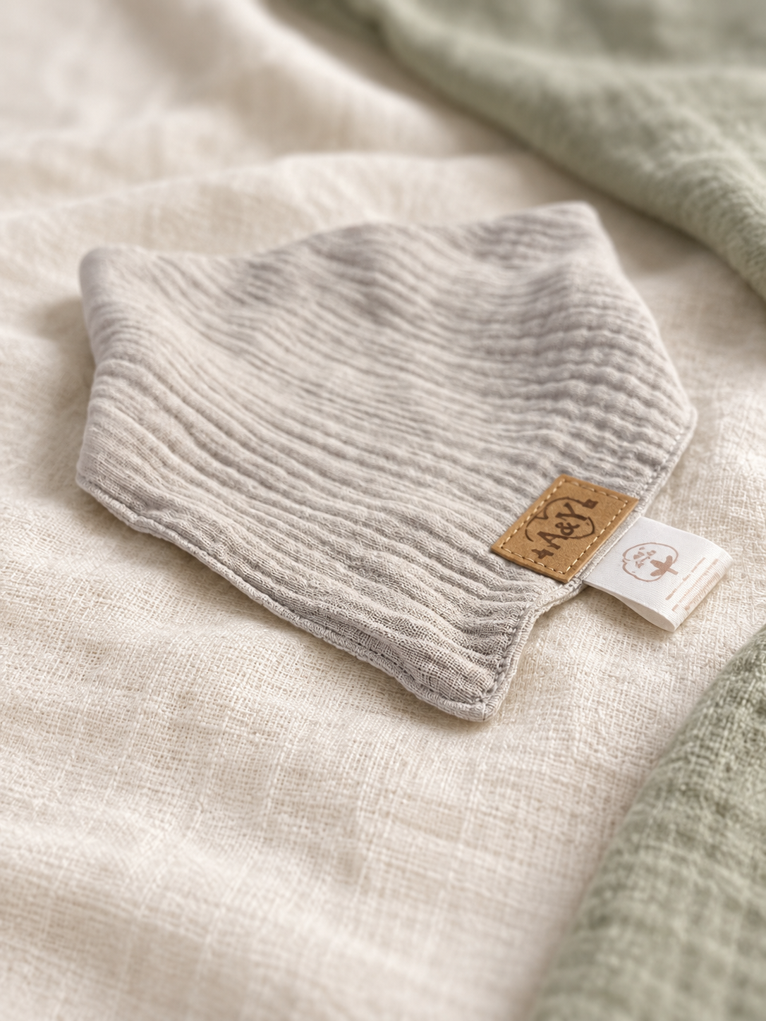 Bavoir bandana MINUS gris présenté de biais avec sa signature A&Y.