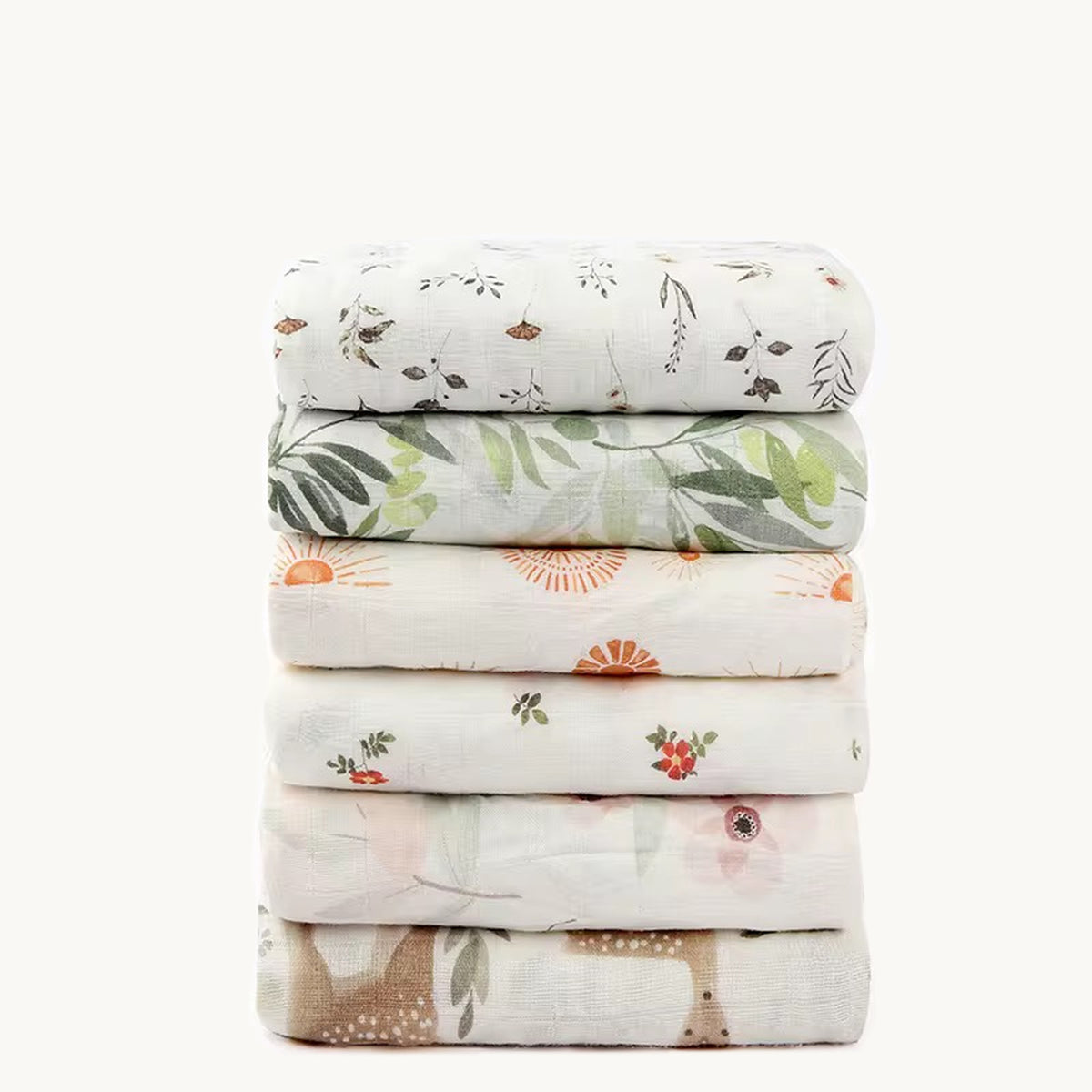 Pile de six couvertures en mousseline bambou et coton avec motifs de feuillage, soleils, fleurs et faons.