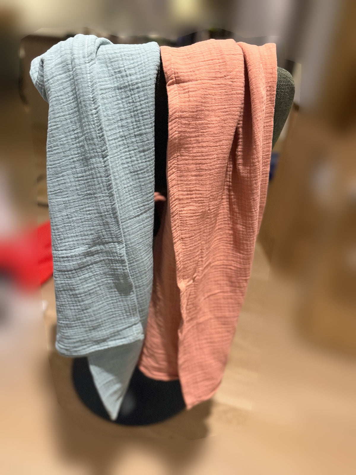 Deux couvertures en mousseline bleu-gris et terracotta présentées côte à côte sur un support.
