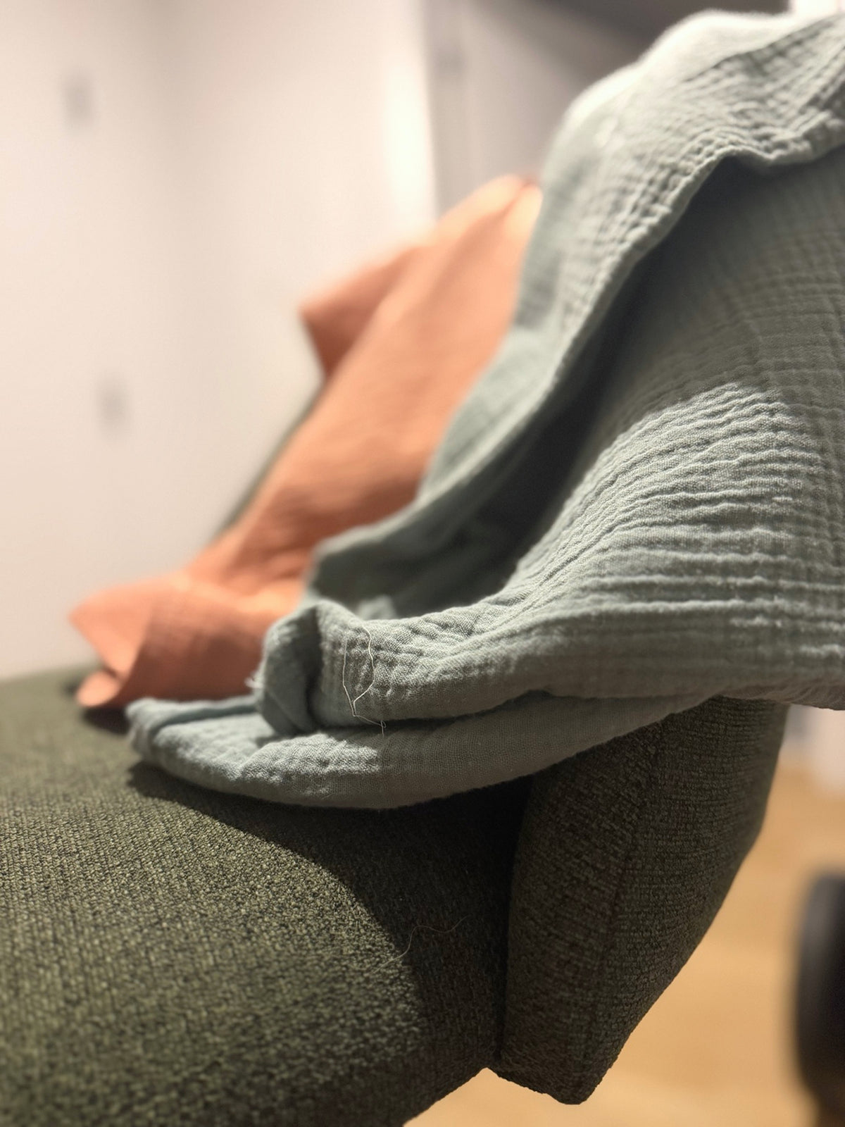 Vue rapprochée de la bordure et des plis de la couverture en mousseline bleu-gris.