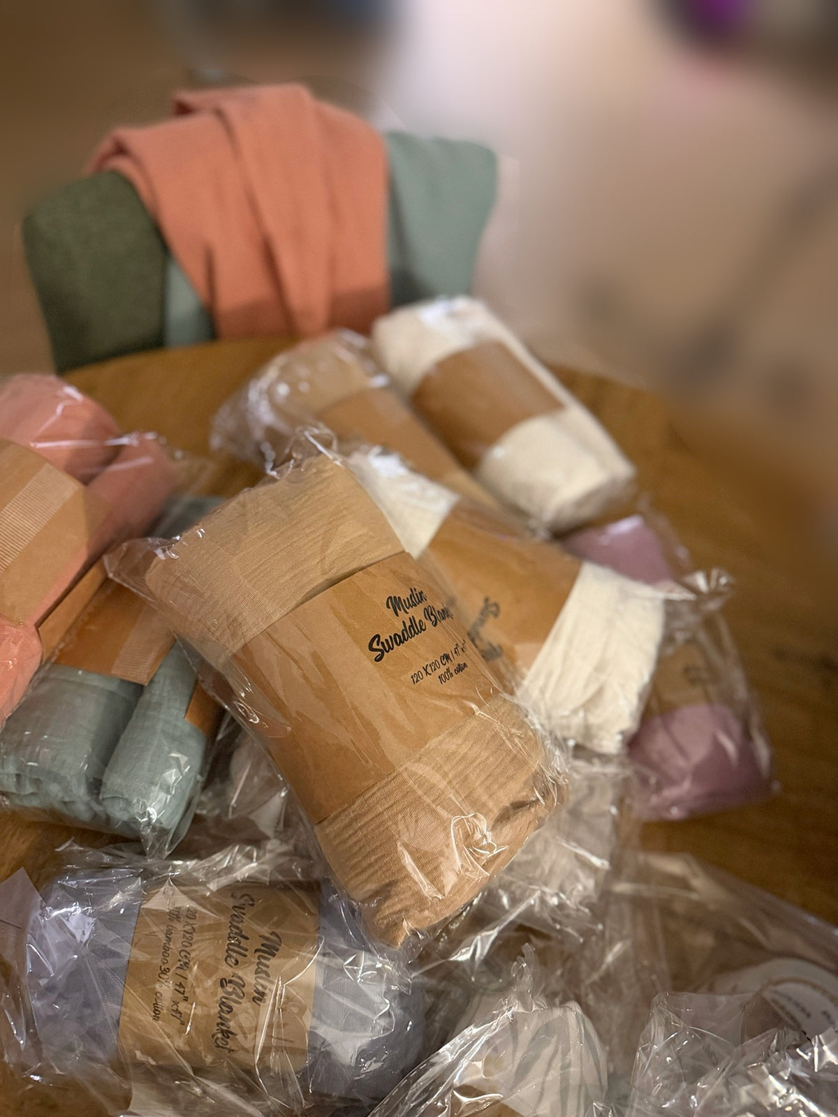 Assortiment de couvertures en mousseline dans leurs emballages, avec un modèle beige au premier plan.