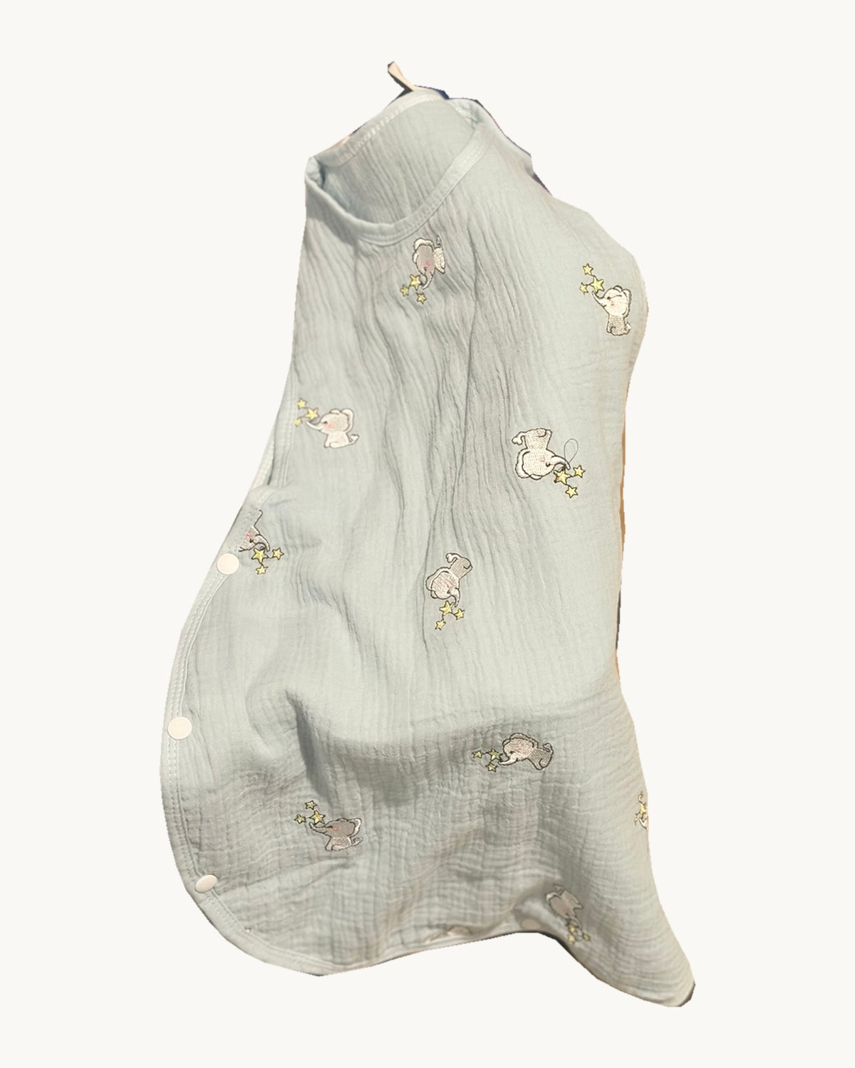 Gigoteuse verte MINUS à motifs éléphants et étoiles, avec boutons-pression latéraux, sur fond blanc crème.