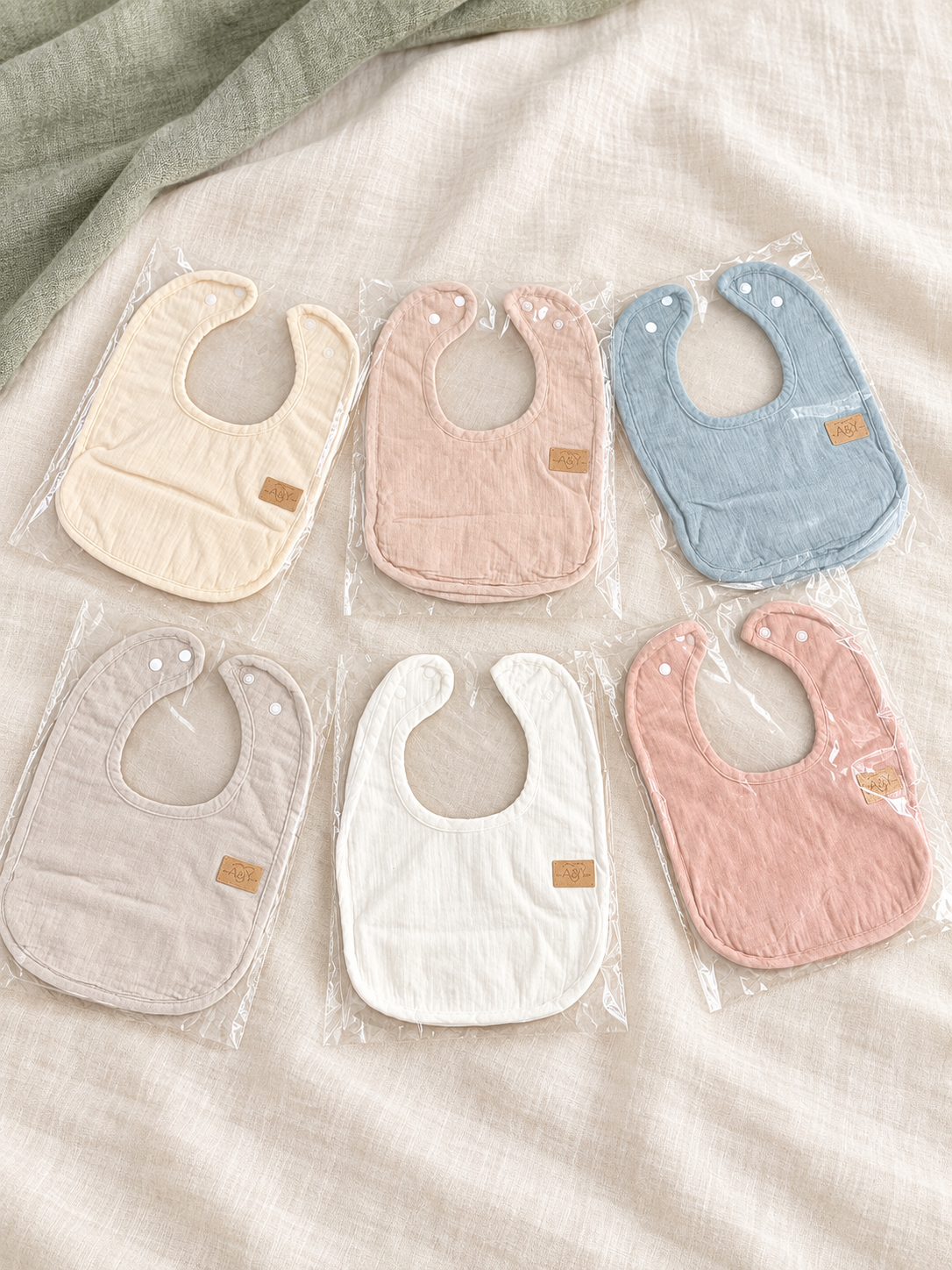 Bavoirs MINUS coton et minky en plusieurs tons doux, présentés de biais.