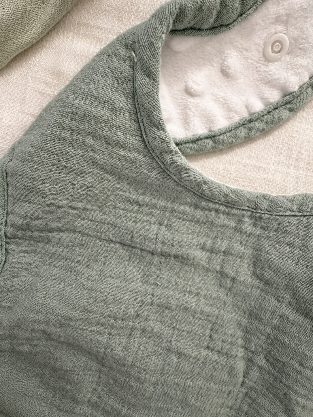 Détail des deux textures du bavoir MINUS : coton sauge et minky blanc à pois en relief.